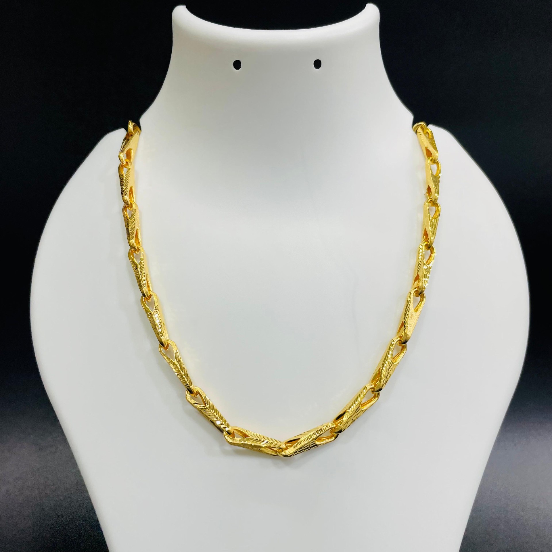 22K gold heavy fancy link chain with feather-engraved bold links displayed on a jewelry bust