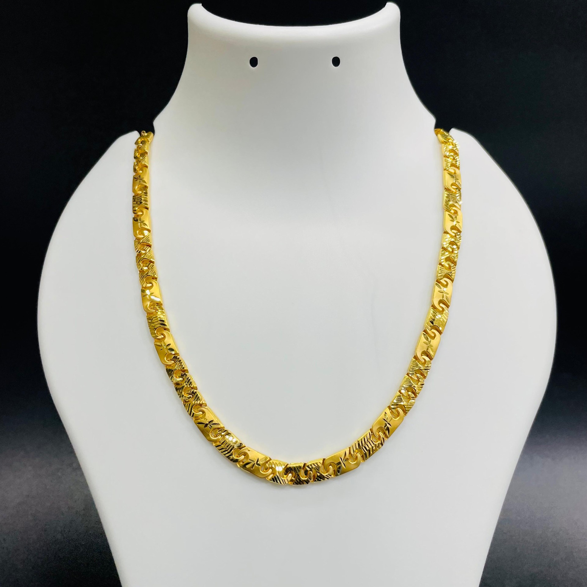 22K gold scroll-pattern flat chain with engraved floral motifs displayed on a jewelry bust