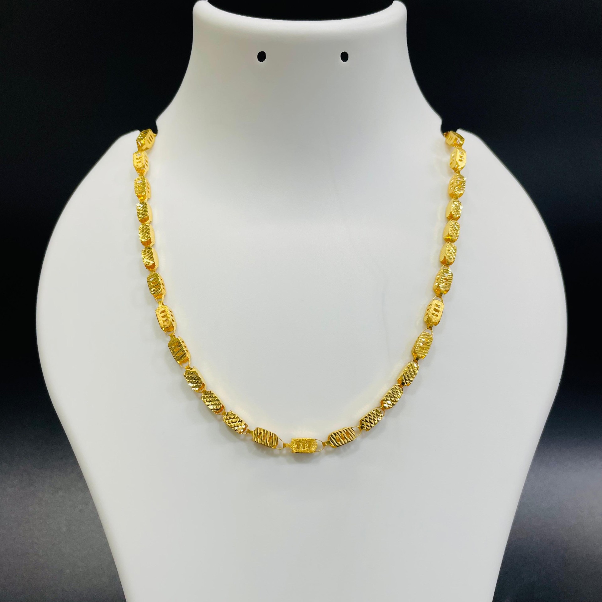 22K gold textured oval link chain with intricate diamond-cut detailing displayed on a jewelry bust
