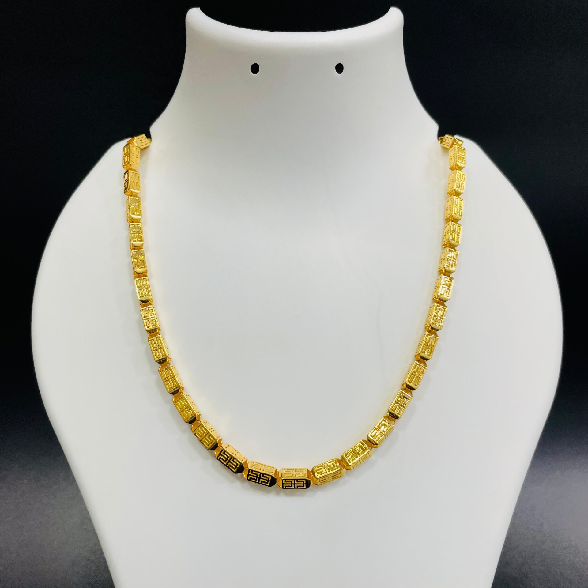 22K gold Greek-key patterned beaded chain with geometric link design displayed on a jewelry bust
