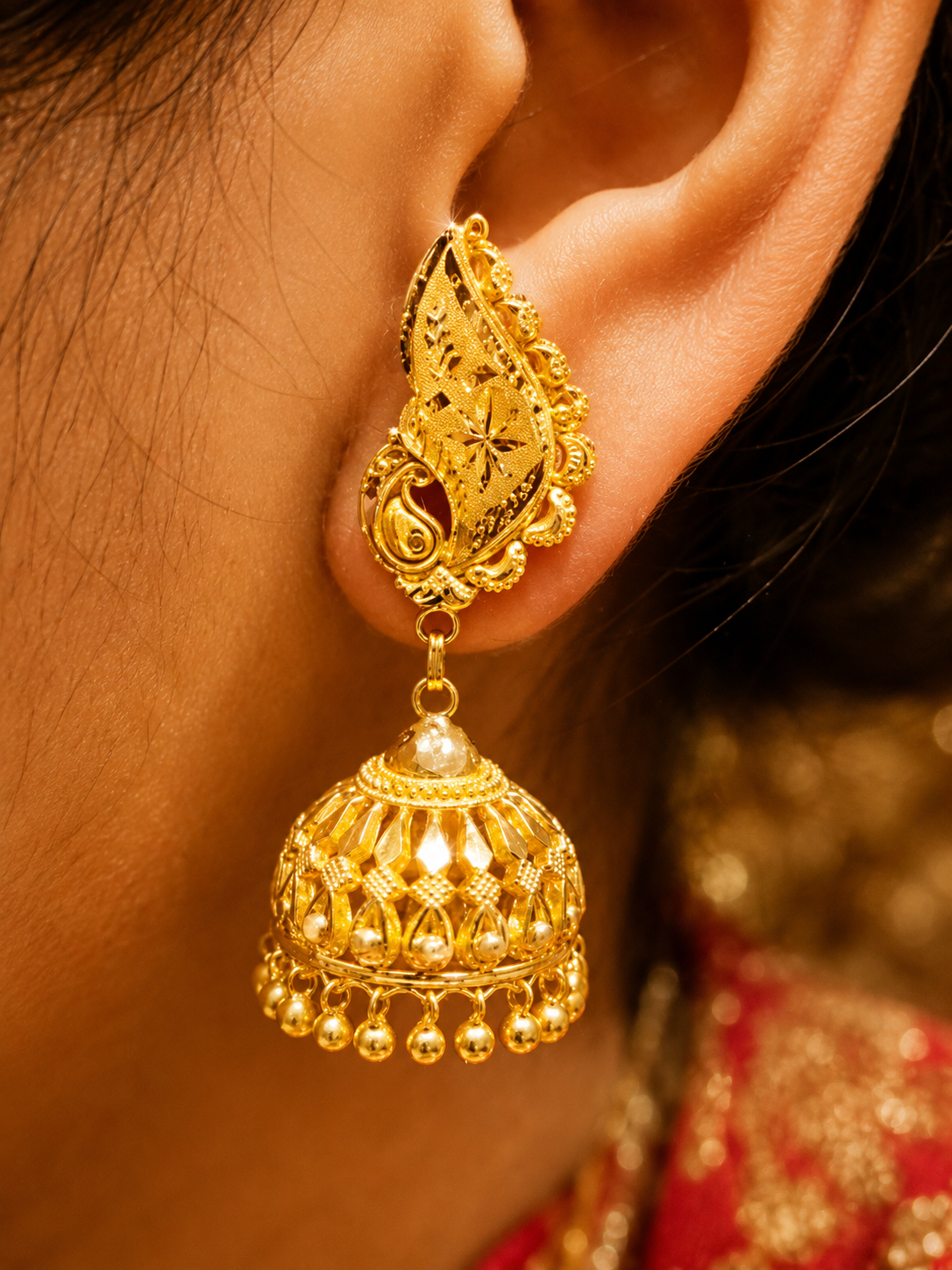 Traditional gold jhumka earring with intricate filigree detail